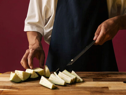 With deft hands, a chef gracefully wields their knife to transform eggplants into a work of art while conjuring the exquisite flavors of "Hünkar Beğendi"