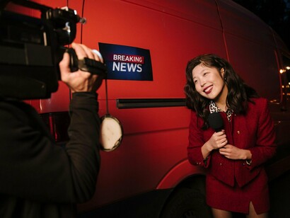 A field reporter standing amid a breaking news scene, representing the urgency and spectacle of live journalism