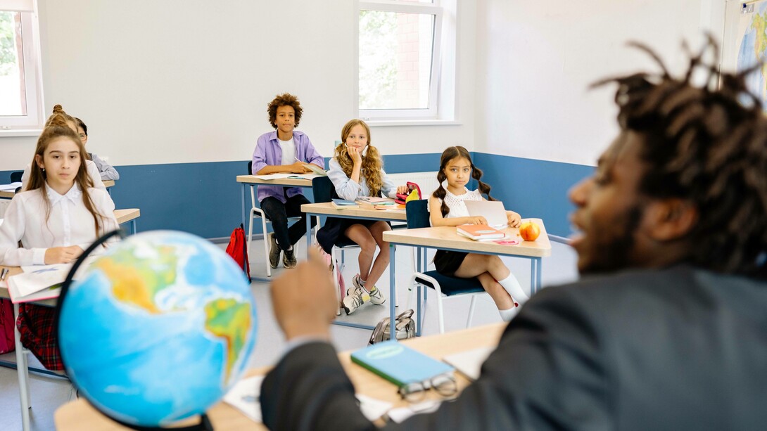 Teacher points to the globe in the classroom