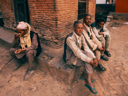 Seated on the roadside, elderly figures embody the harsh consequences of systemic greed and inadequate global governance in the face of mounting global challenges