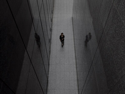 A lone woman strolling amidst towering skyscrapers, symbolizing themes of alienation and individuality