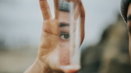 A woman's eye, reflected on a glass shard she's holding