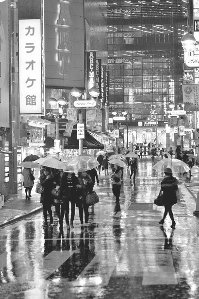 Amidst the bustling crowd on the rain-soaked street, umbrellas created a vibrant and sheltered spectacle