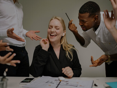 A group of business professionals is discussing in a meeting, but one woman wearing headphones is not paying attention