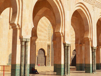 As the golden light filters through the arches, the beautiful tile patterns inside the mosque in Casablanca, Morocco, exemplify the harmony between art and spirituality, fostering an environment where Moroccans gather to celebrate Ramadan’s sacred traditions