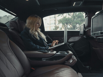 A woman in a upper-end car, working on her computer