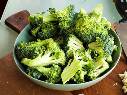 A verdant superfood, fresh broccoli, contrasted against a warm brown wooden chopping board, presents a visually appealing and healthful display