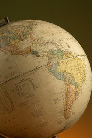 A world map or globe emphasizes the influence of naming, cartography, and the role of geopolitical maps in defining global boundaries