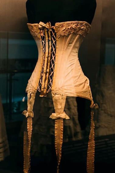 A display of various historical corsets arranged on mannequins in a showcase