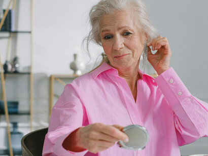 An elderly woman holding a mirror, quietly contemplating the marks of time