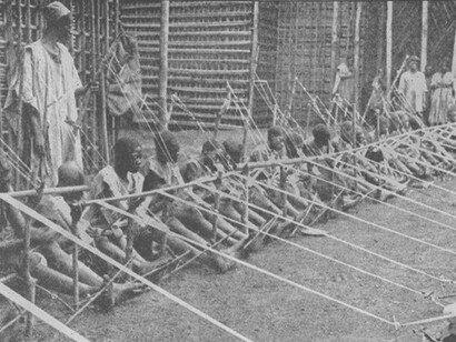 A photograph of Cameroonian children weaving cloth in Kamerun, the final German province in Africa to surrender to the Allies during World War I, illustrating child labor at its most economical