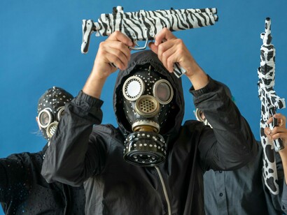 Men in gas masks holding up toy guns in protest