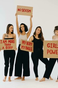 Women in black pants holding placards for women’s rights
