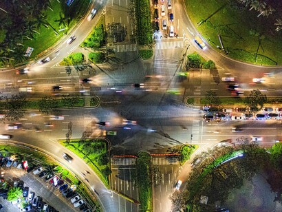Aerial view of a busy road junction illuminated at night, symbolising the complex networks through which people, goods, and services move