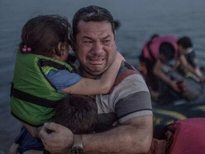Un refugiado sale del mar con su hija en brazos
