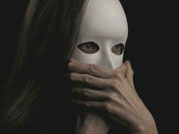 A person wearing a mask with their mouth covered, symbolizing how psychopaths can use fear to silence others