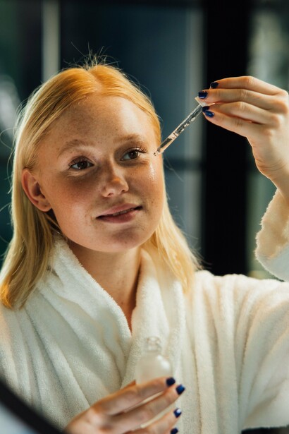 A woman using a dropper to apply a facial serum, symbolizing a measured and intentional approach to skincare