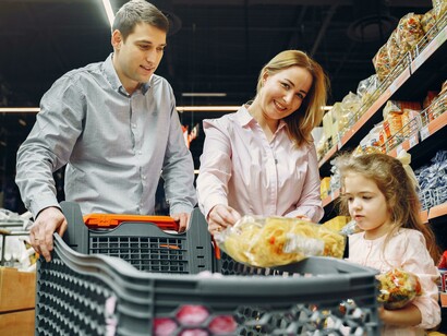 Parent and child grocery shopping, counting coins together at the checkout