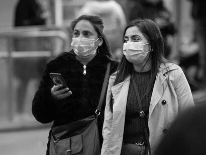 Dos mujeres caminan por la calle usando mascarillas