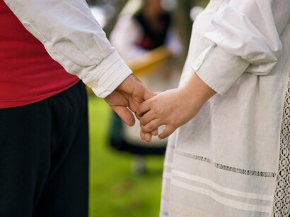 Wearing a folklore dress, a woman, alongside her partner, celebrating cultural identity, diversity, and the vibrant traditions of local festivals