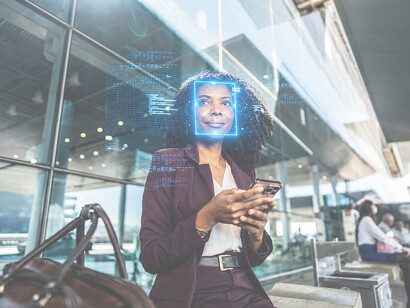 A businesswoman verifies her identity using facial recognition technology on a smartphone at an airport terminal