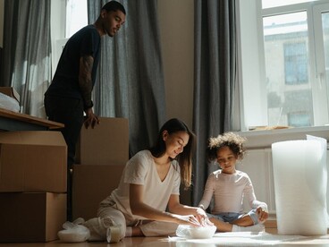 Family unpacking boxes together in their living room after moving into a new home