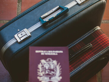 Mérida, Venezuela, a Venezuelan passport rests on a leather suitcase secured with a lock, symbolizing the limitations of a weak passport