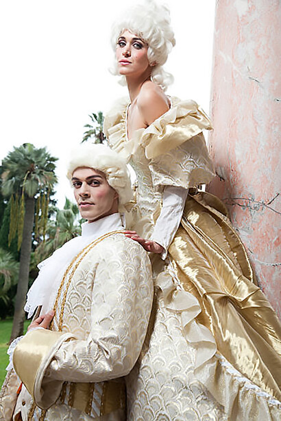 Discover a captivating photograph showcasing an 18th-century French couple, with the woman adorned in the opulent fashion of Marie Antoinette, embodying luxury and extravagance