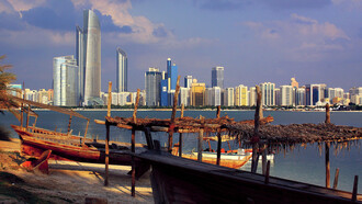Skyline of Abu Dhabi, UAE, with boats moored at the shoreline 
