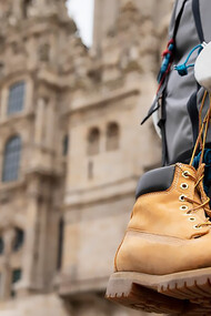 A male traveler with a backpack and dangling shoes exploring a historic cathedral in Europe