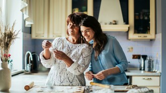 A woman in a blue long-sleeve shirt cooking in the kitchen with her mother