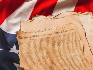 The Declaration of Independence carefully displayed with the American flag, reflecting the values of liberty, justice, and equal rights