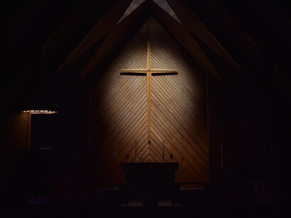 Cruz iluminada en una iglesia a oscuras