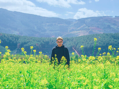 A man standing in a field of wildflowers, representing the value of reflection and independent thought away from digital distractions