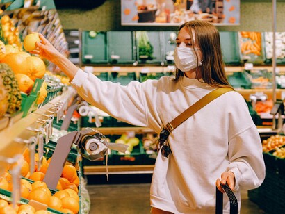 A woman food shopping at the supermarket is feeling the ripeness of the produce
