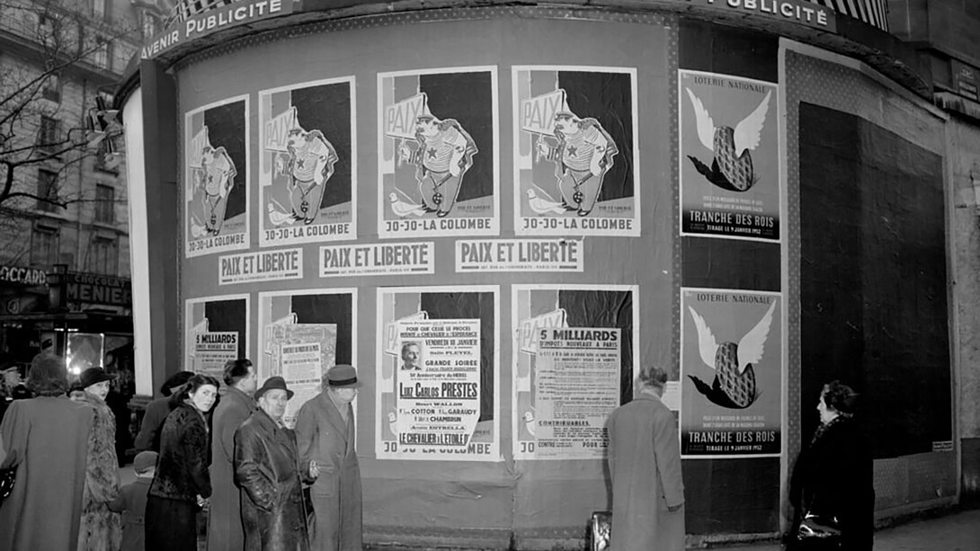 Political posters in Paris, such as the "Jojo la Colombe" caricature of Stalin, represent the intense battle against communism during a turbulent period in history