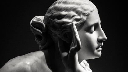 Estátua feminina faz gesto com a mão para escutar