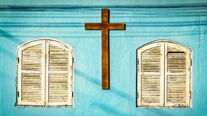 A wooden cross on a light blue wall
