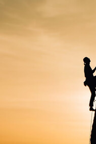 Scaling life's peaks metaphorically, the arduous climb reflects the challenges of achieving success and wealth, mirroring the uphill struggle toward prosperity