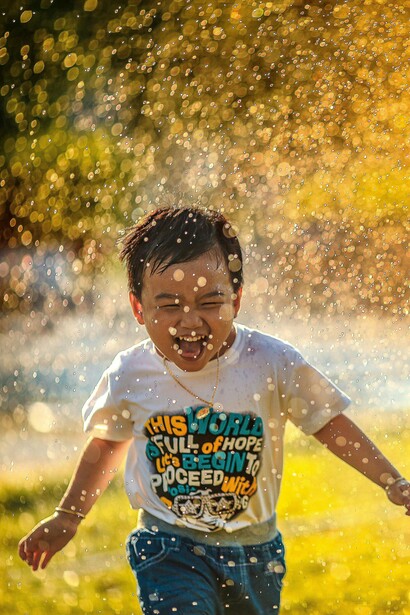 Bimbo che ride tra spruzzi d’acqua: “passeggiate nella natura offrono stimoli visivi e uditivi reali, che favoriscono uno sviluppo cognitivo equilibrato”