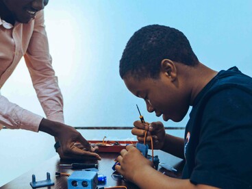 Two students connecting electronic components during a hands-on tech class in Accra, representing the value of practical education in preparing young people for a changing world