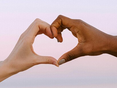 Two hands of different skin tones form a heart, symbolizing unity amidst diversity and highlighting the importance of breaking down barriers of disconnection