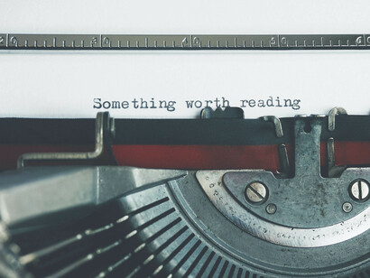 Antigua máquina de escribir con el mensaje "Algo que valga la pena ser leído"