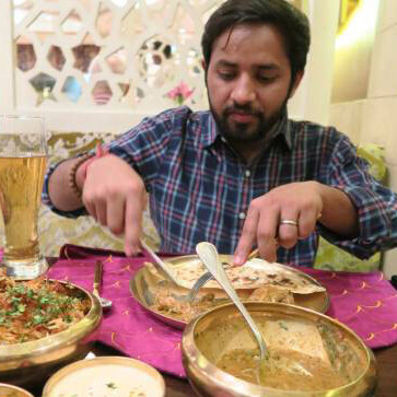 A Hindu man enjoying dinner at an Indian restaurant table, featuring a traditional Lucknowi biryani