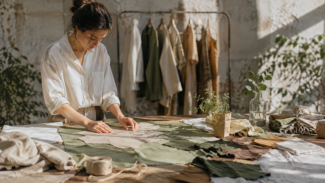 A designer carefully arranging fabric pieces across a worktable, representing the zero waste philosophy of finding purpose for every part of a textile