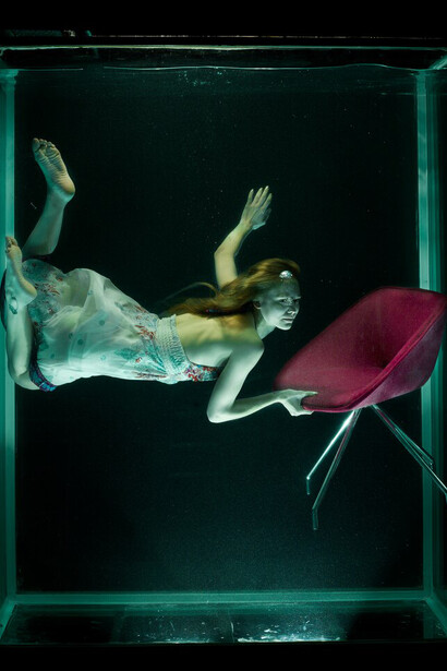 A woman in water with a red chair, capturing the essence of digital surrealism