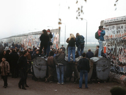 Crowds watch from the West German side as the Berlin Wall is dismantled at Potsdamer Platz, with an East German policeman directing the scene