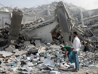 Palestinians inspect the ruins of Watan Tower after it was destroyed in Israeli airstrikes in Gaza City on October 8, 202, Palestine