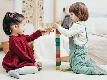 Durante uma atividade lúdica, duas crianças exploram brinquedos e interagem com o ambiente. As experiências concretas e as brincadeiras constituem oportunidades de descoberta e participação no processo de aprendizagem. Para Jean Piaget, a criança participa ativamente da construção do conhecimento ao agir sobre os objetos e explorar as relações que estabelece com o mundo