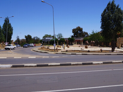 A landscaped roundabout featuring metal sculptures of Basotho warriors, identifiable by their shields and spears